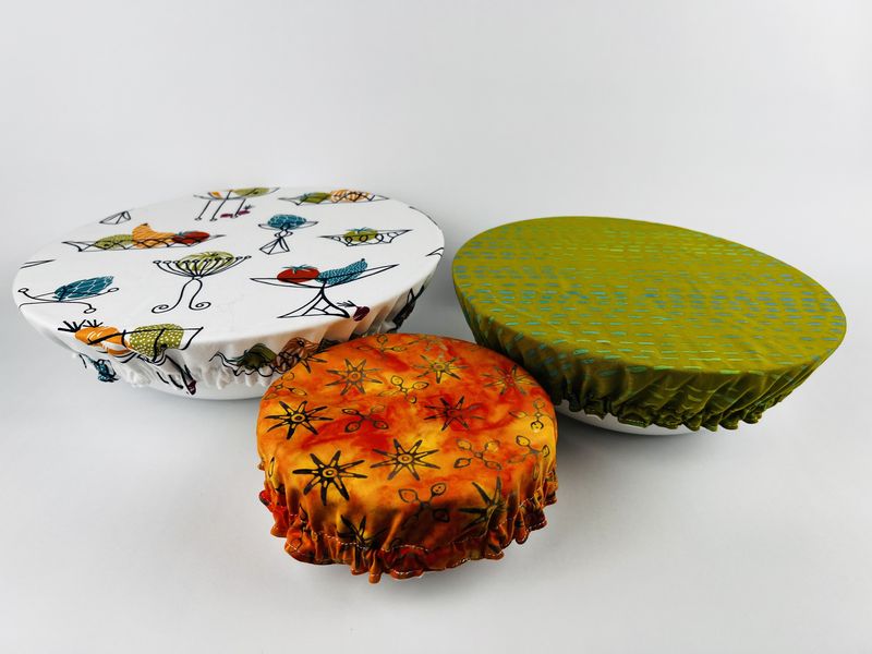 Three fabric bowl covers in bird, orange and green prints