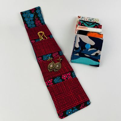 Travel jewelry roll opened to show earrings, beside folded pouches