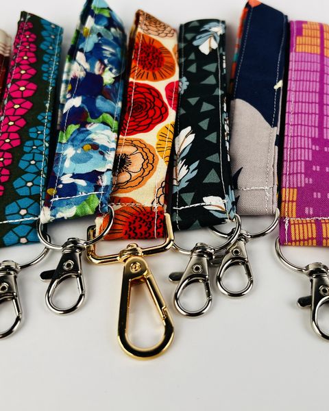 A row of fabric wristlet key fobs with metal clasps